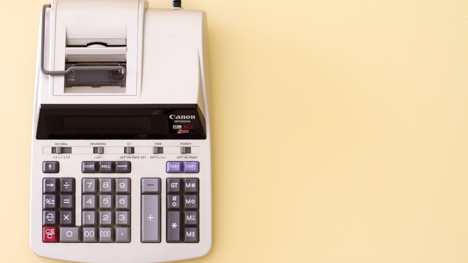 Canon MP20DII calculator with tax and cost calculation buttons on a light yellow background.