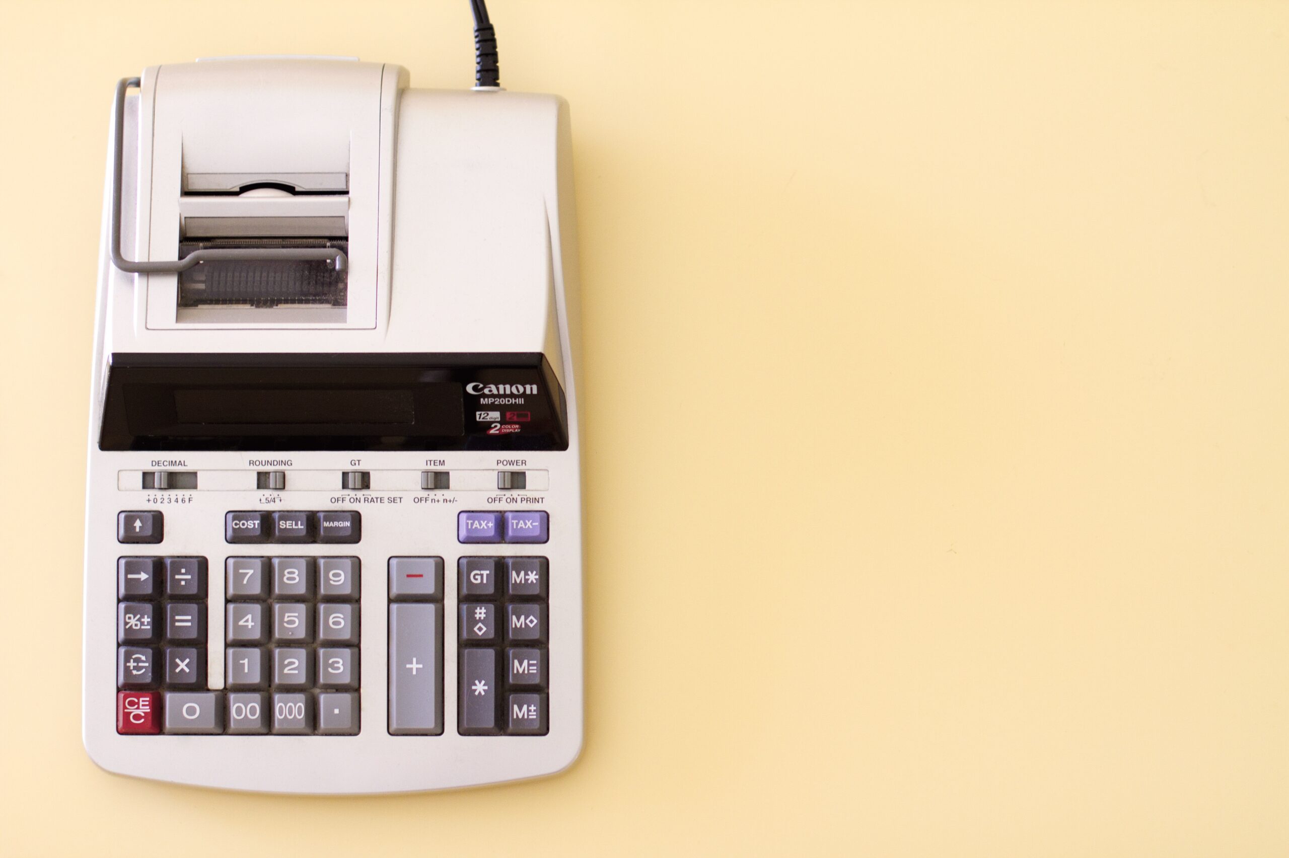 Canon MP20DII calculator with tax and cost calculation buttons on a light yellow background.