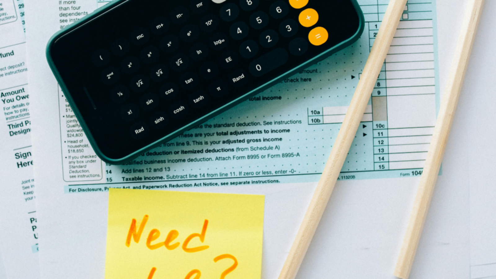 Close-up of a calculator displaying 1,000,000 on a smartphone screen, placed on top of tax documents with a yellow sticky note reading 'Need help?' and two pencils beside the papers.