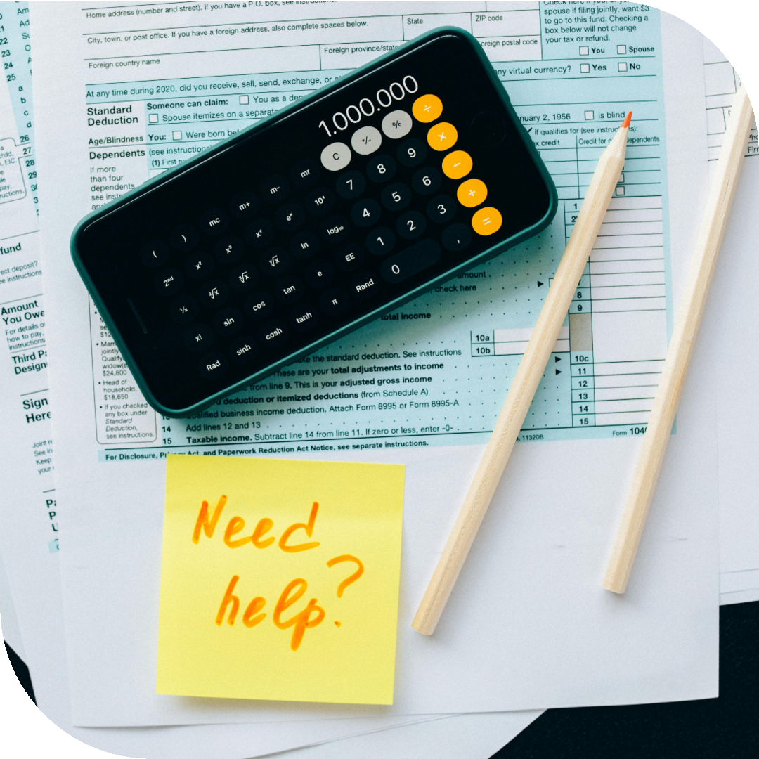 Close-up of a calculator displaying 1,000,000 on a smartphone screen, placed on top of tax documents with a yellow sticky note reading 'Need help?' and two pencils beside the papers.